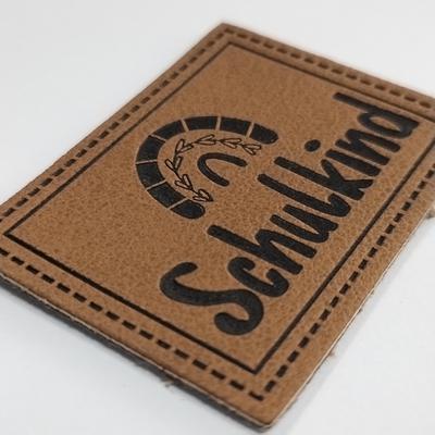 Microfiber a gravé le label en refief en cuir d'unité centrale de logo cousent sur l'habillement adaptent la conception aux besoins du client