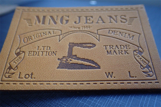 Les jeans écologiques garnissent en cuir des labels de correction ont gravé Logo For Uniform en refief