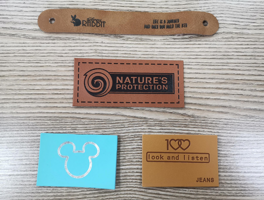 Les labels de vêtement ont gravé la correction en refief en cuir cousent sur le logo d'unité centrale d'habillement